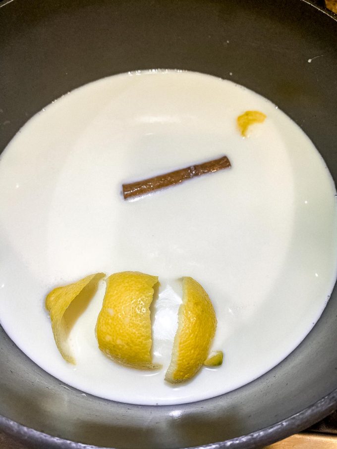 Milk, lemon peel and a stick of cinnamon in a saucepan