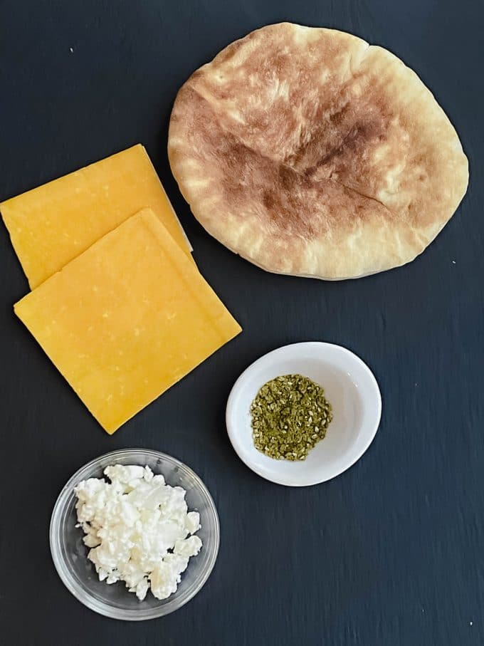 ingredients to make grilled cheese pita sandwich: pita bread, cheddar cheese, zaatar and feta cheese