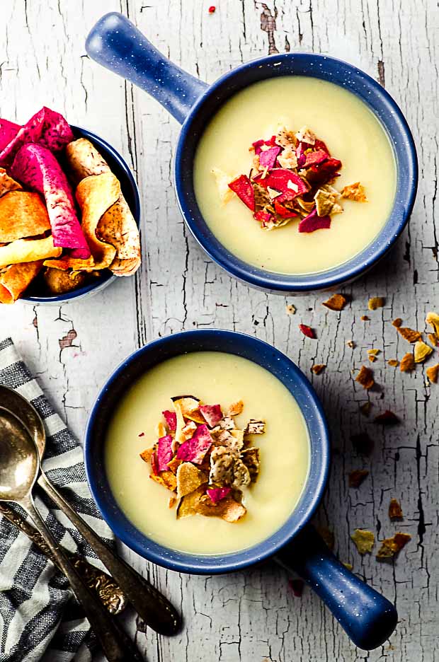 bird's eye view of two bowls of celeriac soup topped with vegetable chips
