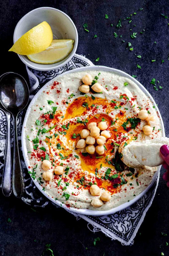 Scooping some hummus out of a plate with a piece of pita bread