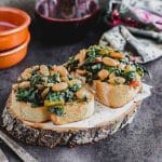 Side view of two slices of sourdough bread with sautéed chard with cannellini beans