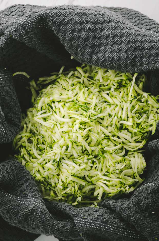 Shredded Zucchini on a clean kitchen towel ready to be squeezed to make Cheese Zucchini Frittata