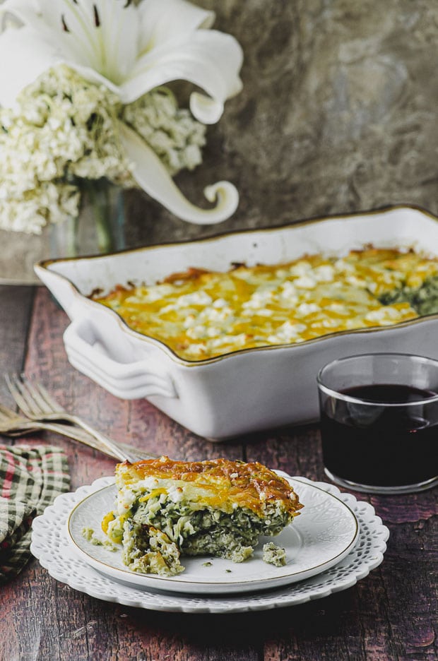 Side View of a white plate with a piece of cheese zucchini frittata, with a ceramic baking pan in the background