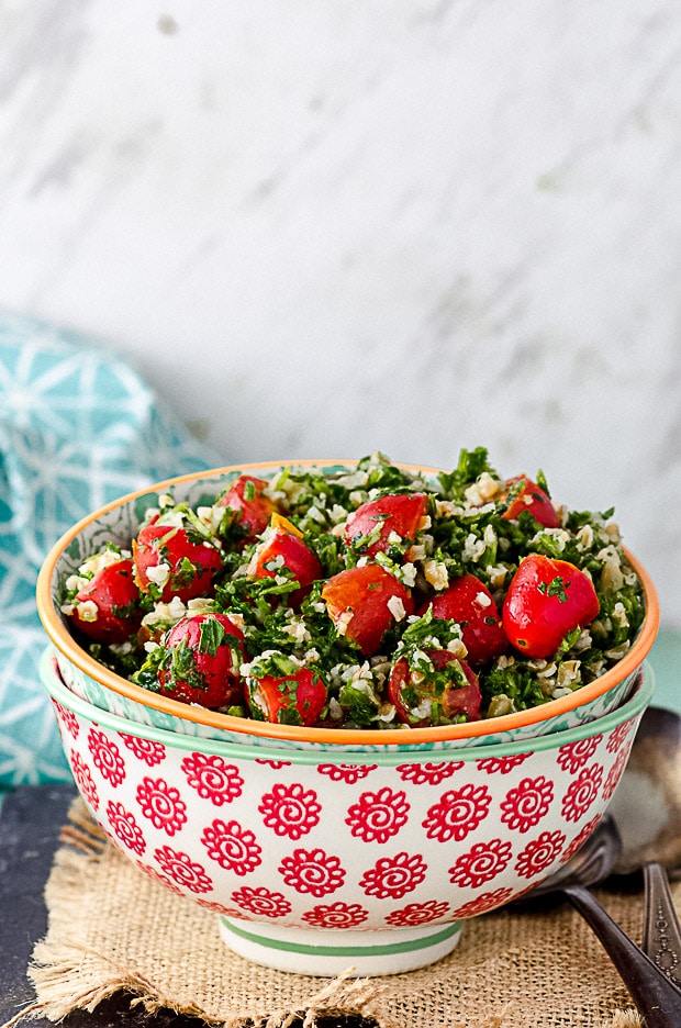 A red and white bowl filled with tabbouleh salad