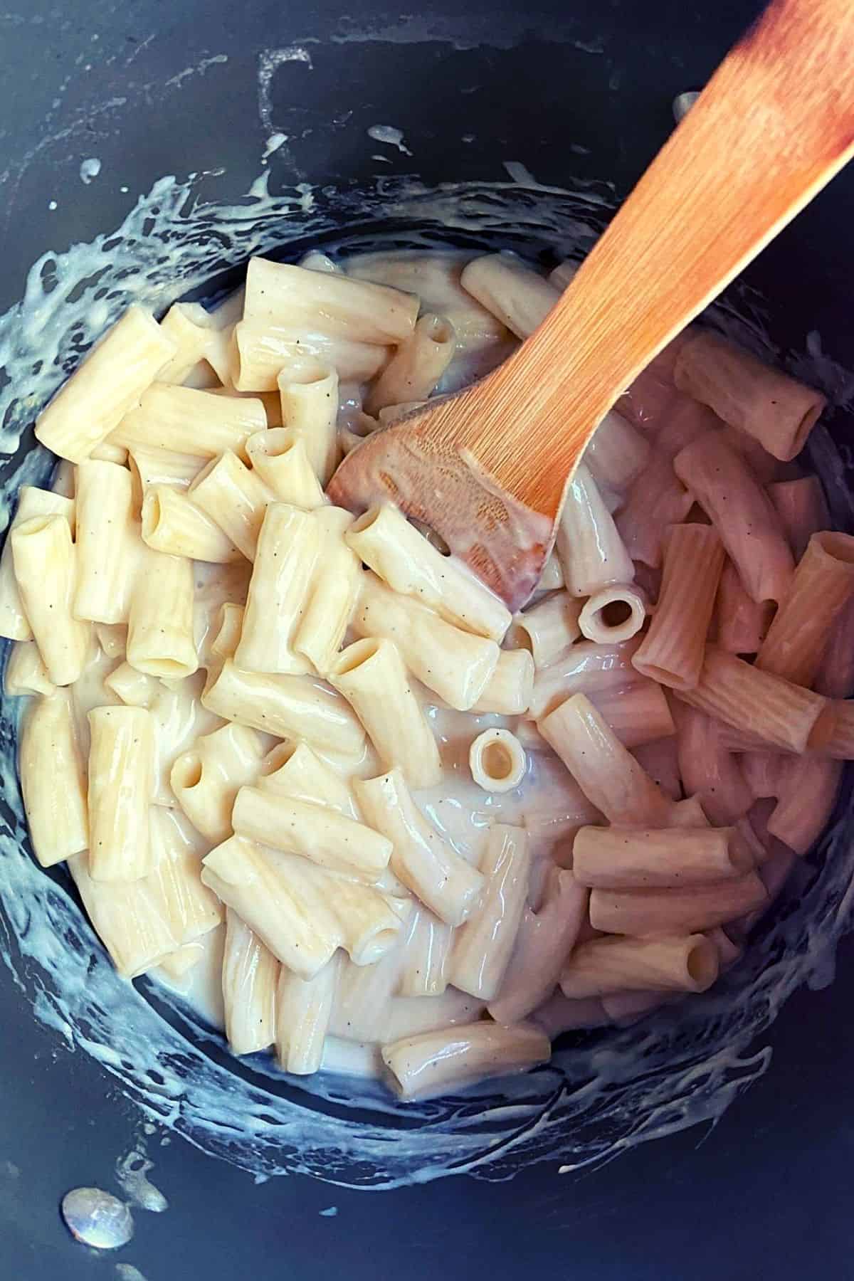 Overhead view of pasta after being mixed with cheese mixture with wood spoon