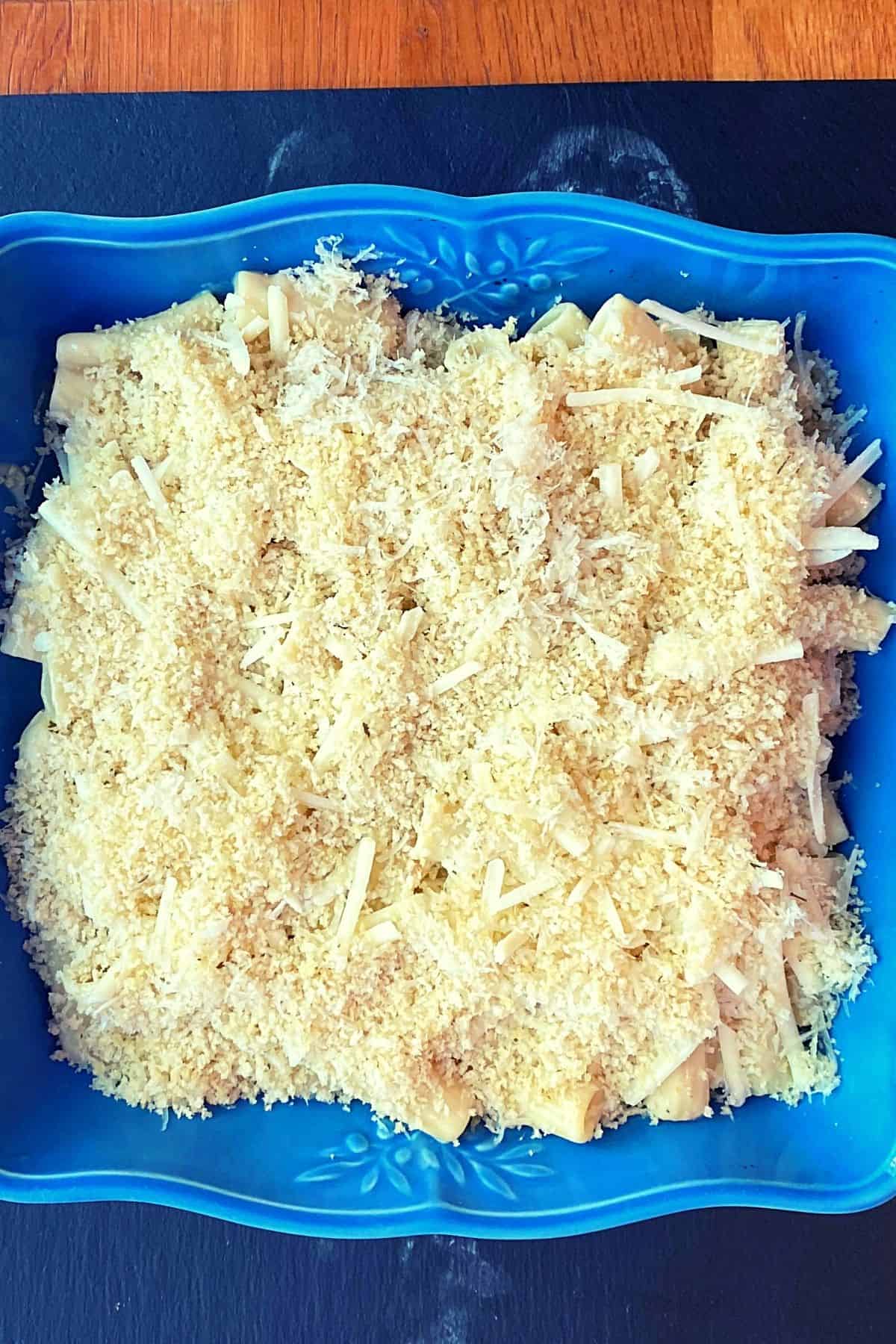 Overhead view of bread crumb and cheese sprinkled over pasta before baking