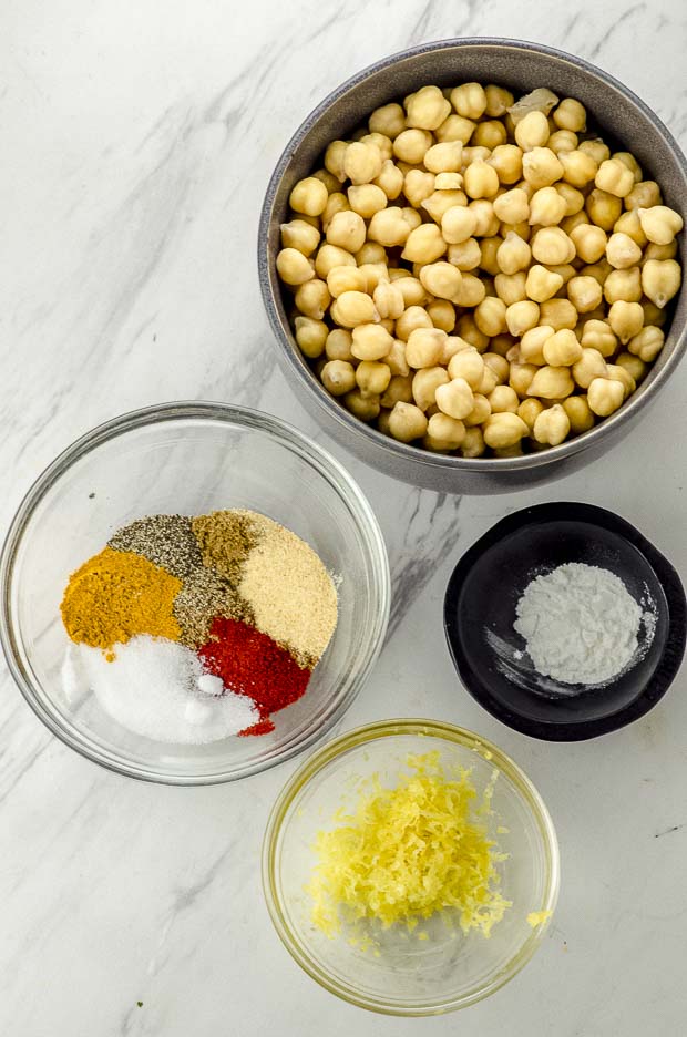 Bird's eye view of 4 bowls with chickpeas, spices, baking powder and lemon zest