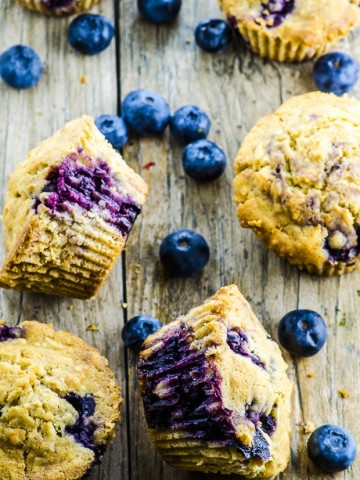 5 blueberry coconut muffins scattered on a wooden surface