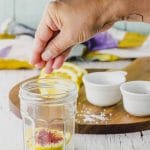 Sprinkling salt and paprika on a jar of preserved lemons
