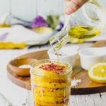 Drizzling olive oil on a jar of preserved lemons