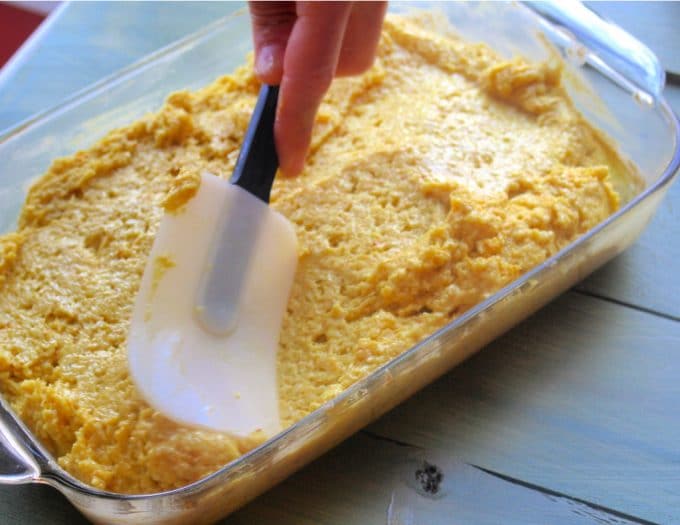 Spreading the turmeric cake ingredients on a baking pan