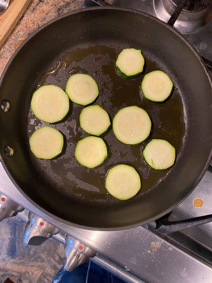 An overhead view of zucchini slices on a skillet