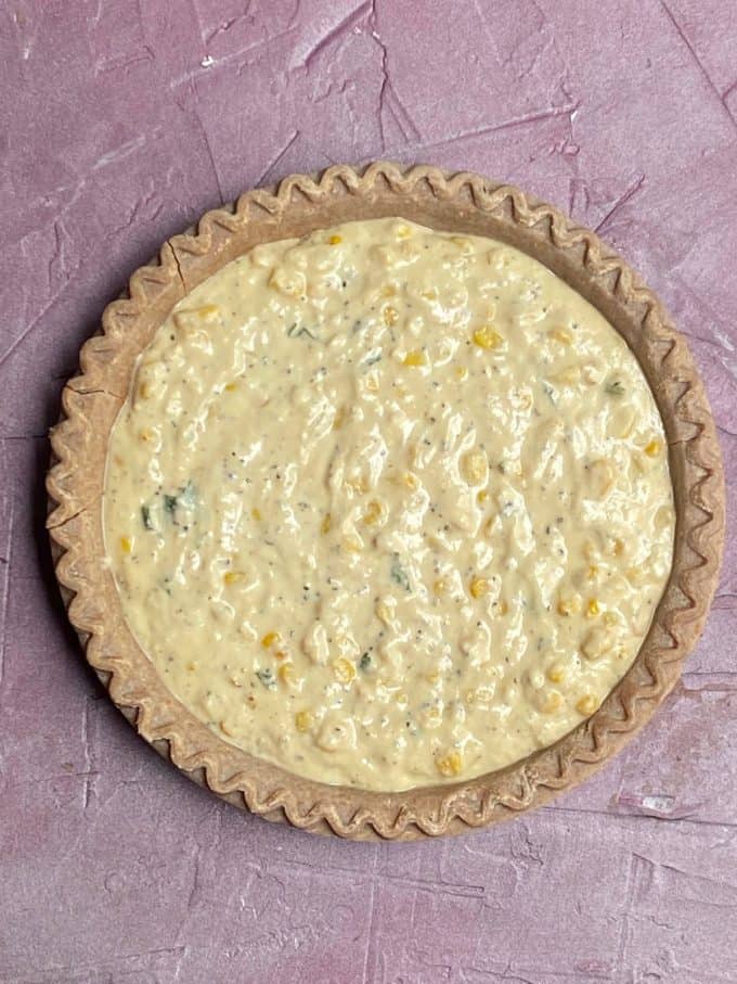 An overhead view of pie crust with dairy free zucchini quiche batter poured on top