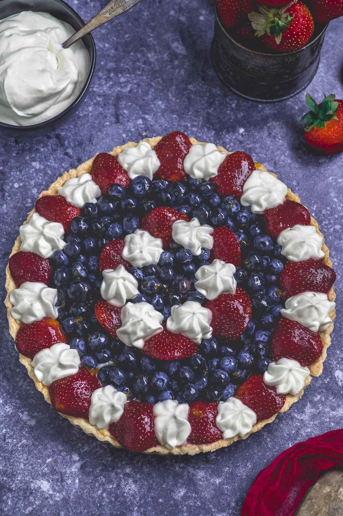 overhead view of a read white and blue fruit tart
