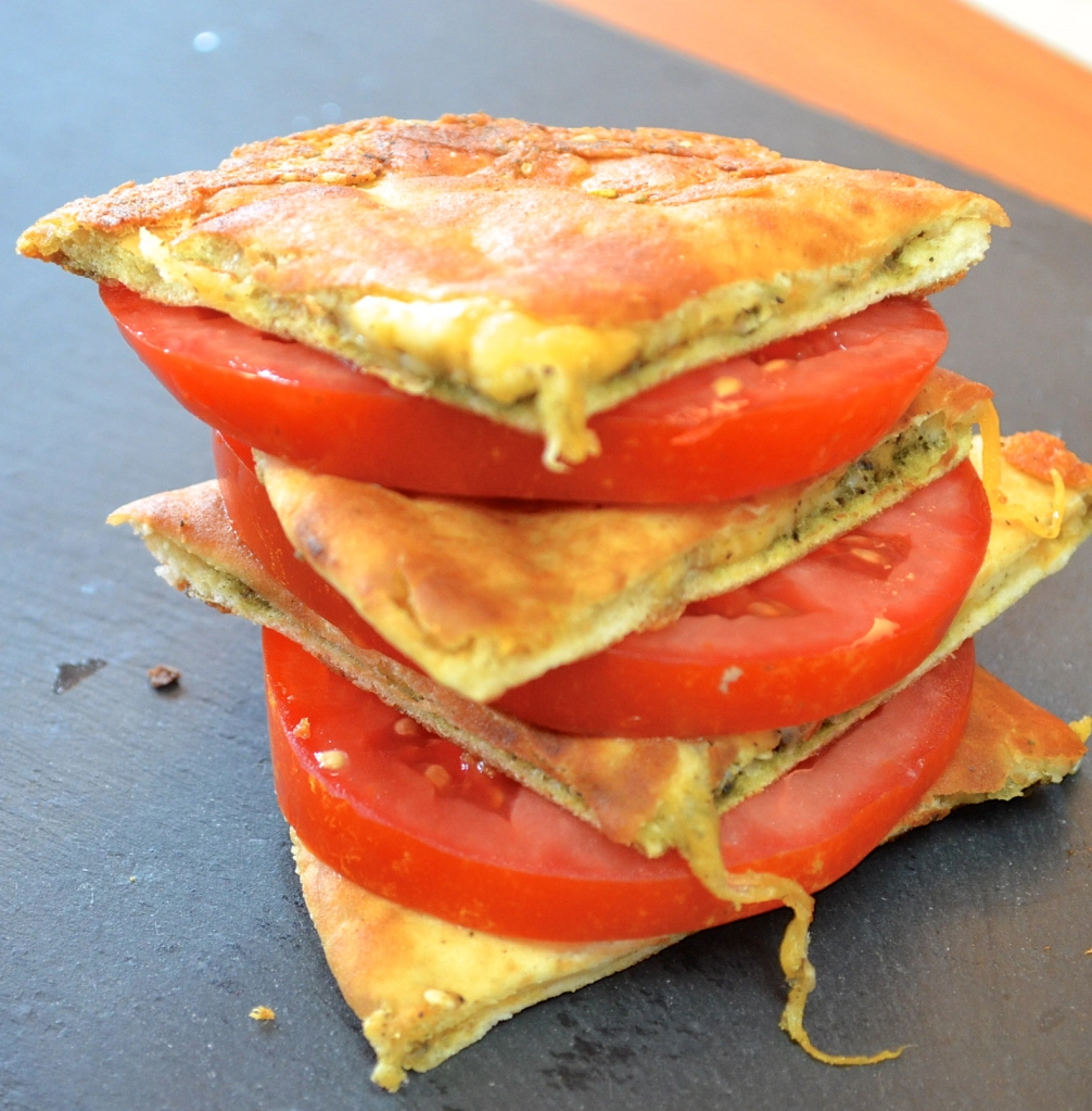 Pita grilled cheese sandwich stacked and with a slice of tomato between each slice
