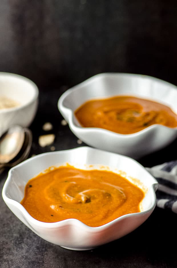 Side view of two white bowls of creamy tomato and roasted eggplant soup