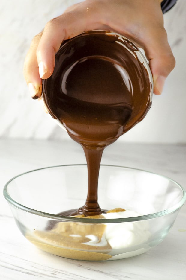 pouring melted chocolate in a bowl with Greek yogurt and peanut butter