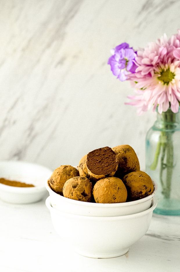 Side view of 2 stacked white bowls filled with chocolate truffles