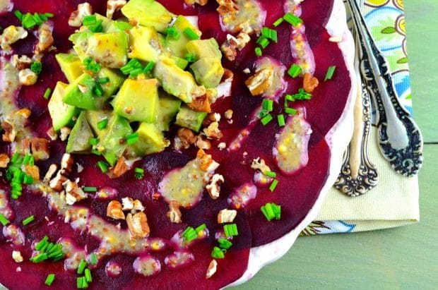 Bird's eye view of a beet carpaccio salad topped with avocado and a chia dressing