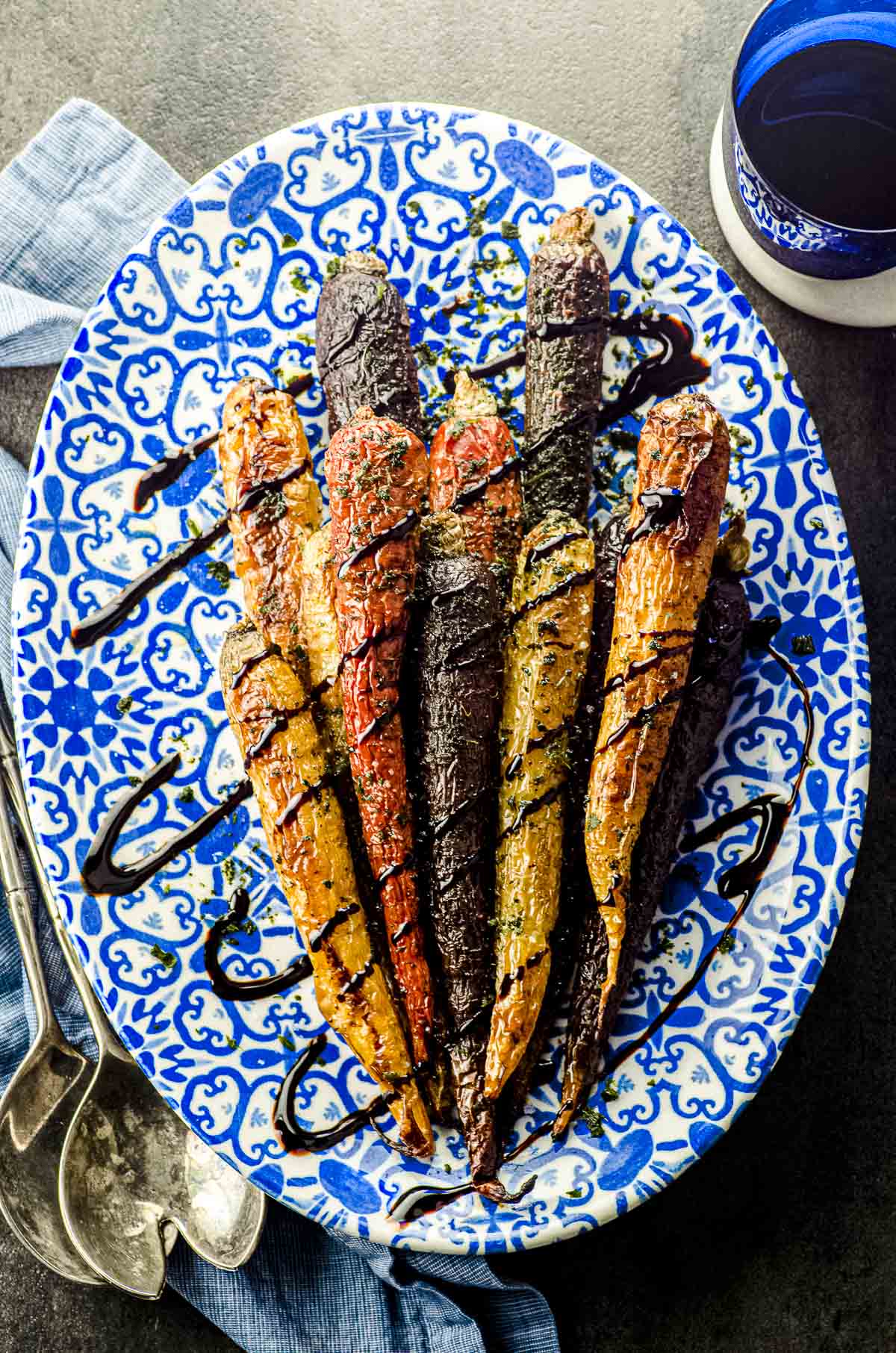 Overhead view of a blue patterned oval serving dish with rainbow carrots and drizzled with balsamic glaze