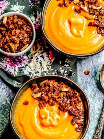 An overhead view of two bowls of carrot soup