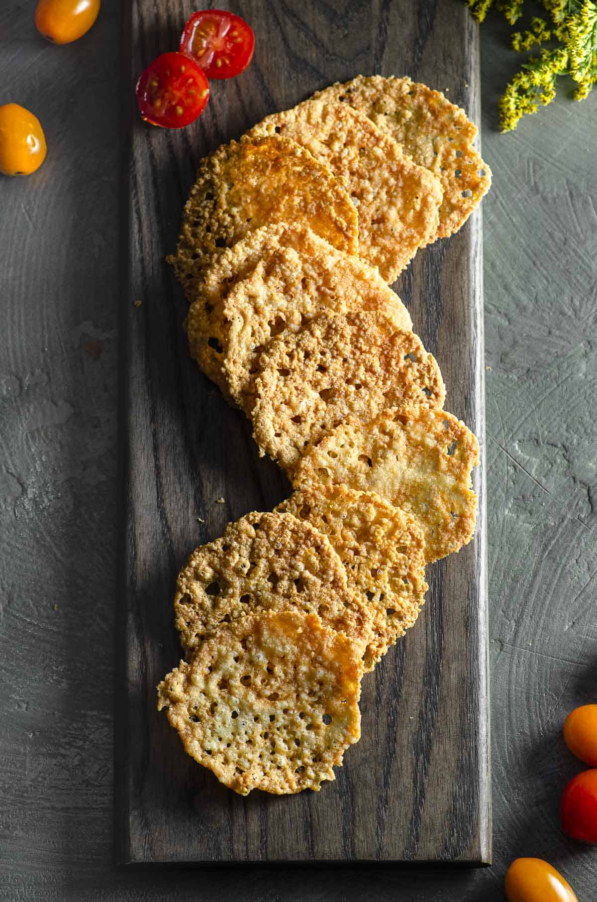 overhead view of some overlapping parmesan crisps on a wood board