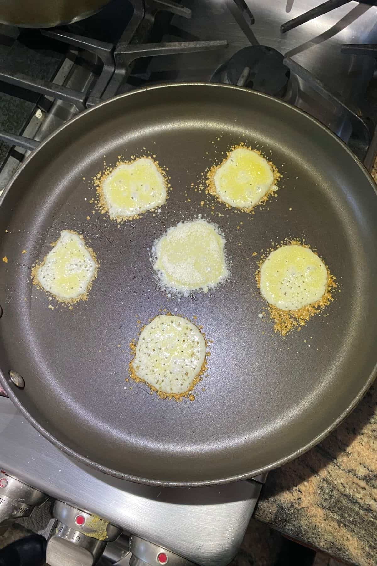Parmesan cheese being fried onto a nonstick pan to make crisps