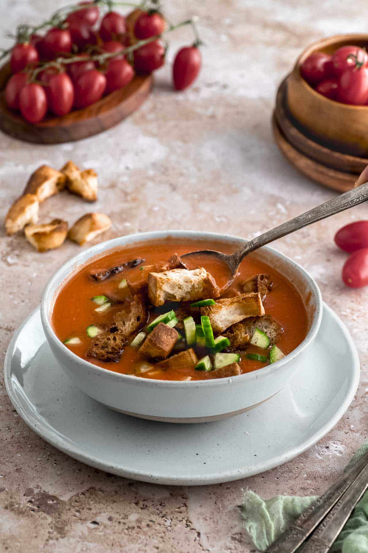 a bowl of gazpacho with a spoon picking up a crouton
