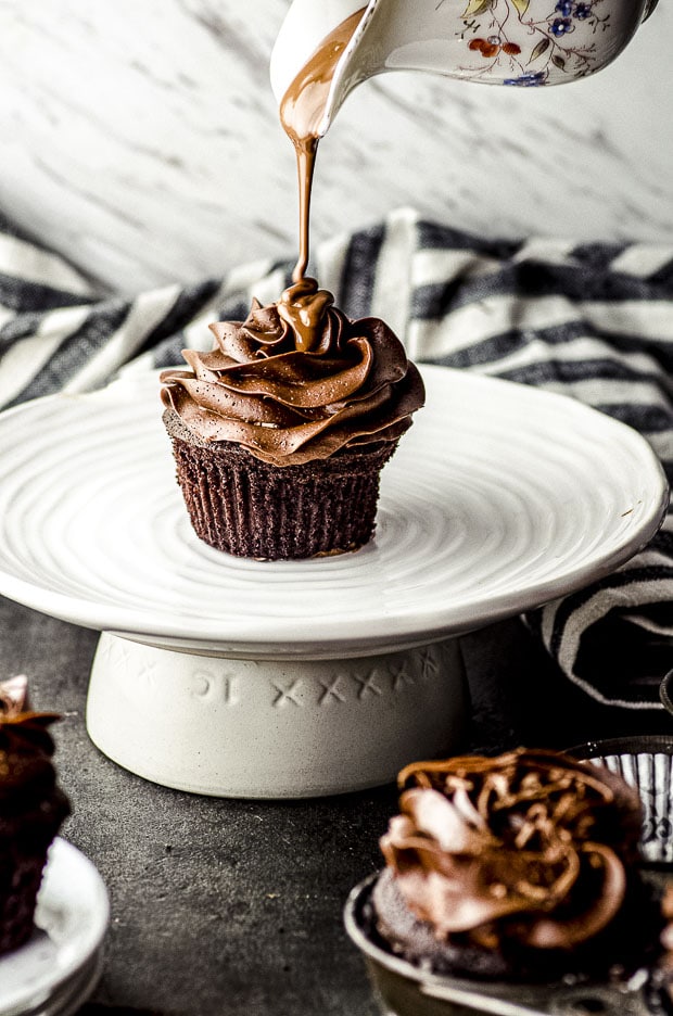 Pouring melted chocolate on a chocolate cupcake with chocolate frosting