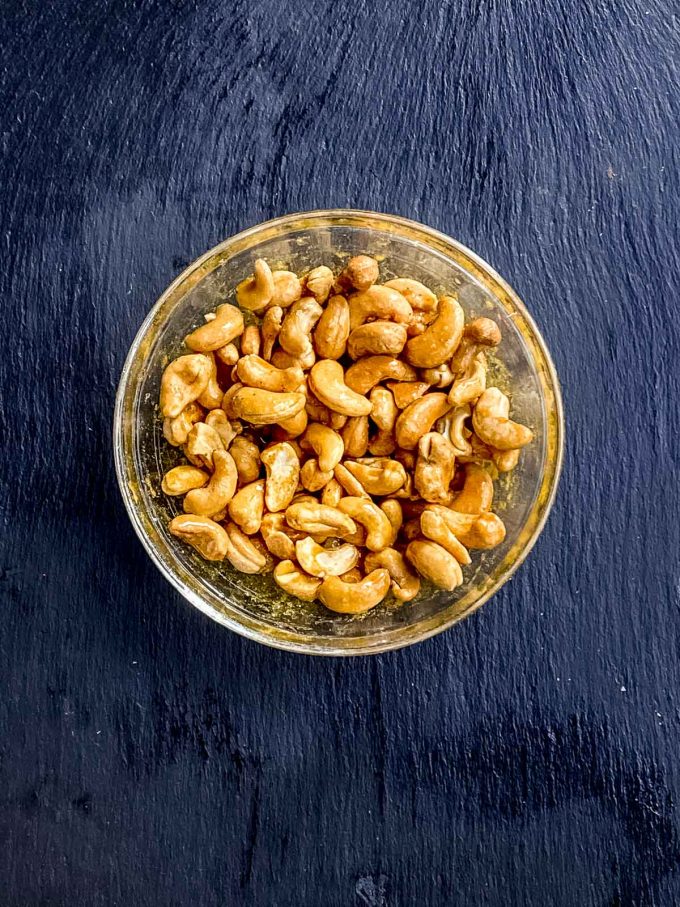 cashews, maple syrup, turmeric and black peppers combined in a glass bowl
