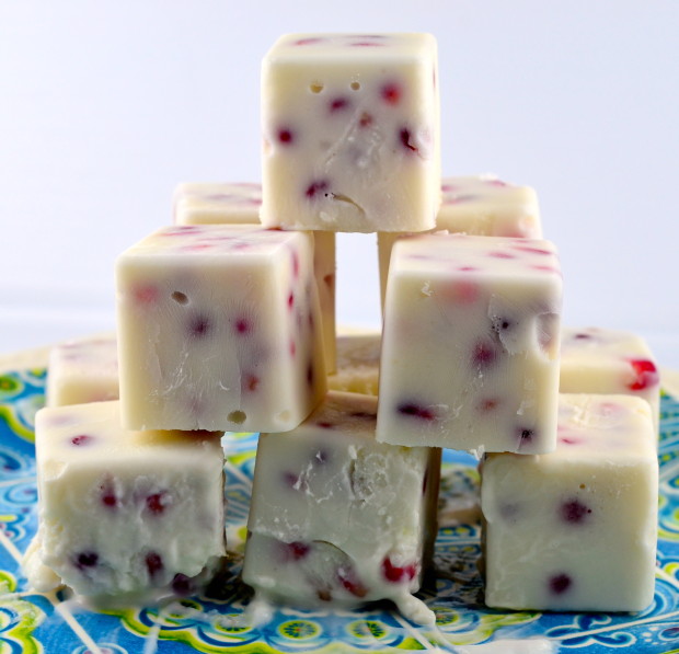 Close up of Frozen Greek Yogurt and Pomegranate Bites (Cubes) stacked in a pyramid fashion on a blue matt