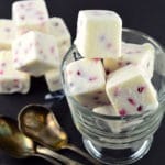 Close up of Frozen Greek Yogurt and Pomegranate Bites (Cubes) stacked inside a clear glass