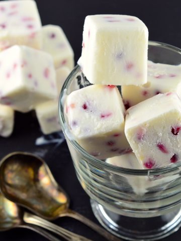 Close up of Frozen Greek Yogurt and Pomegranate Bites (Cubes) stacked inside a clear glass