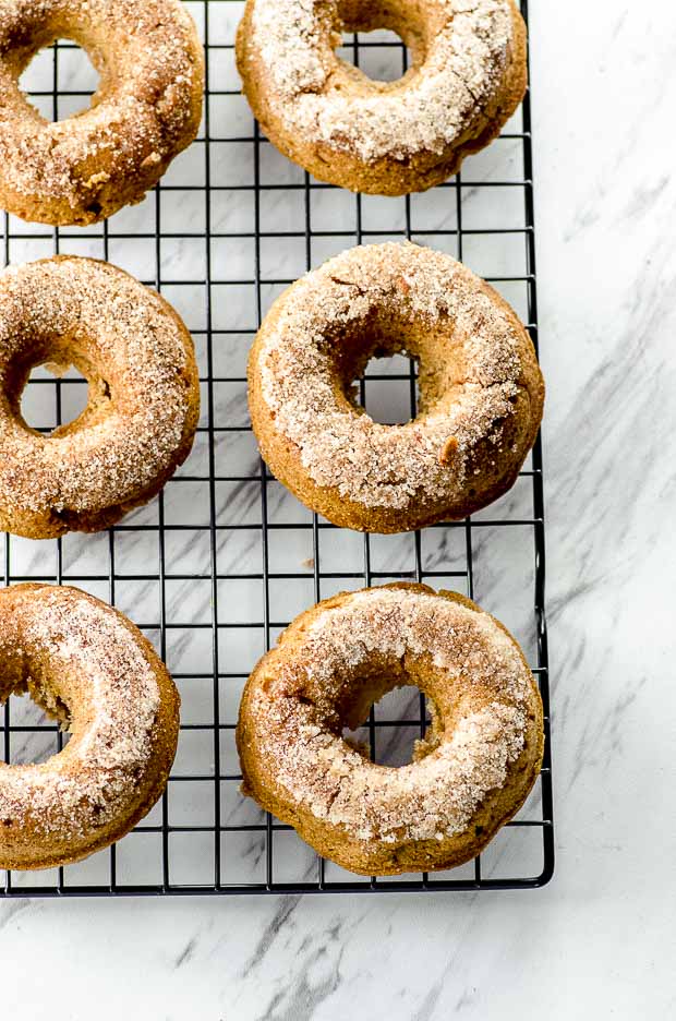 apple cinnamon donuts lined on a cooling rack