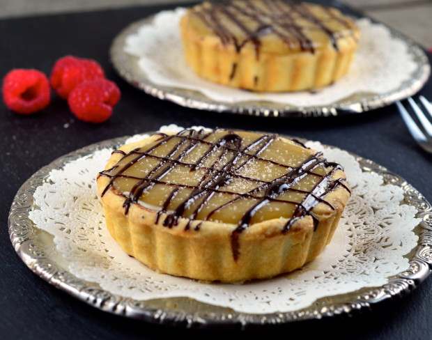Two Vegan Salted Caramel Chocolate Tartelettes set on two silver plates.