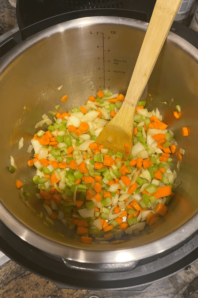 An overhead view of a pot of carrots, celery and carrots chopped and being sauteed
