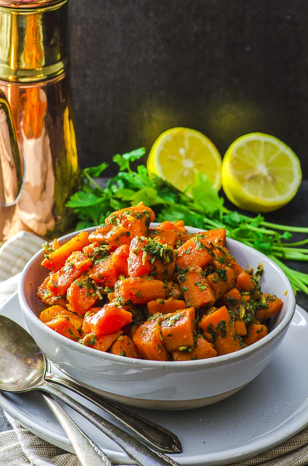 A Bowl of moroccan carrot salad with a lemon cut in half on the background. One of our vegetarian Passover recipes.