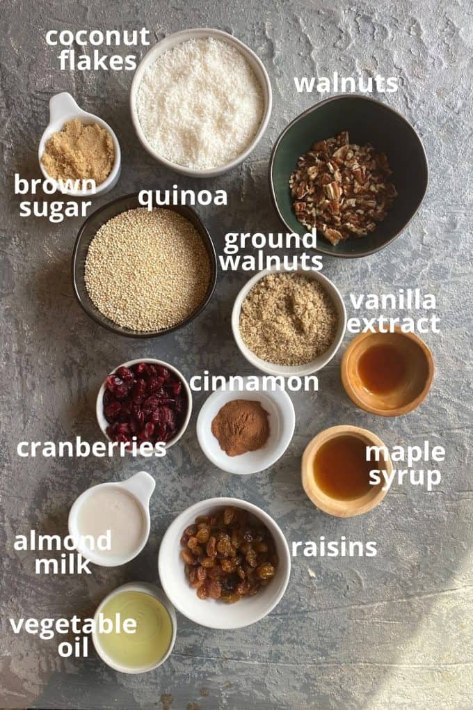 An overhead view of the ingredients to make quinoa granola; coconut flakes, brown sugar, walnuts, ground walnuts, quinoa, maple syrup, vanilla, cinnamon, cranberries, raisins, vegetable oil, almond milk