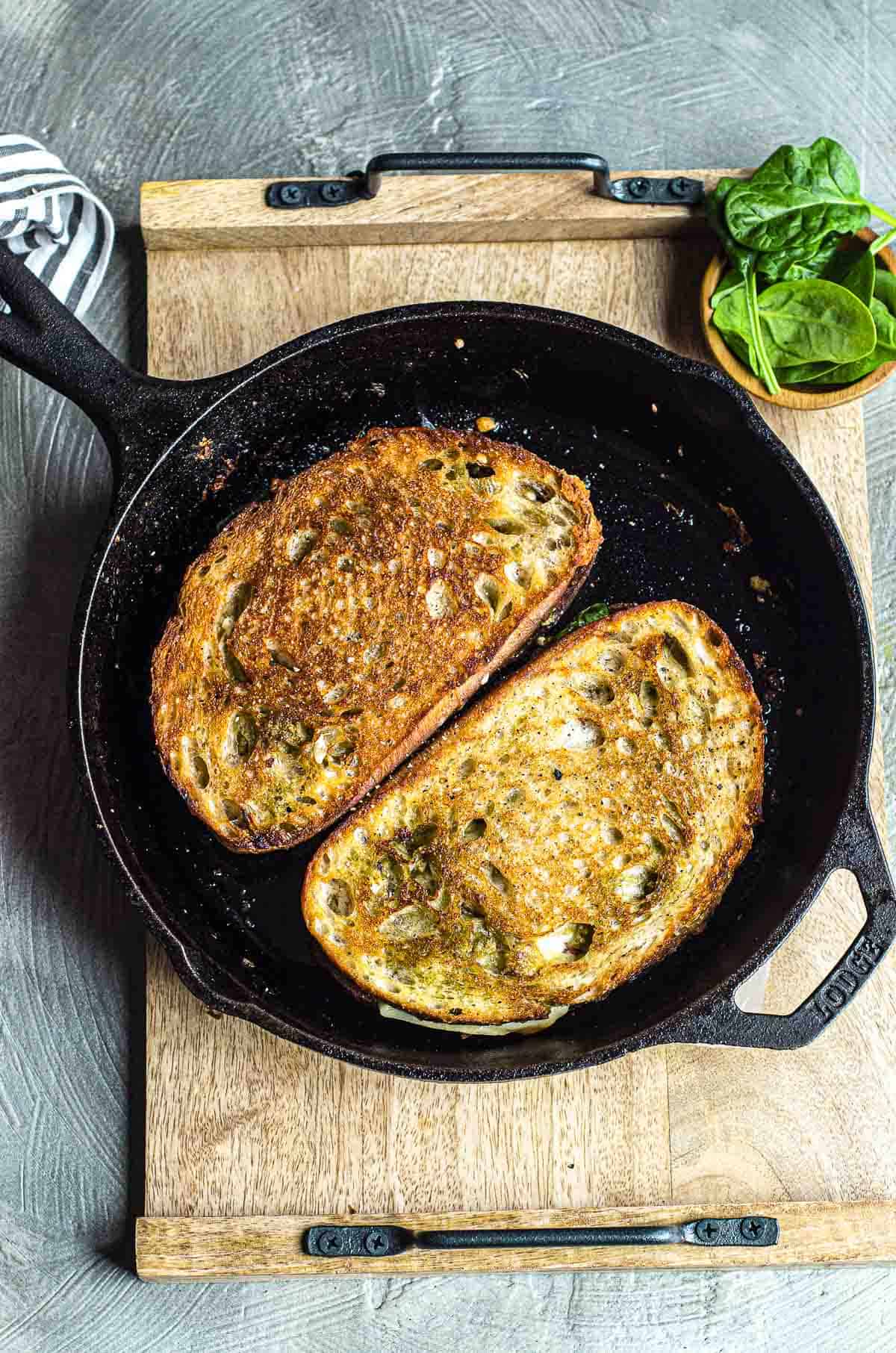 Two grilled cheese sandwiches in a cast iron pan