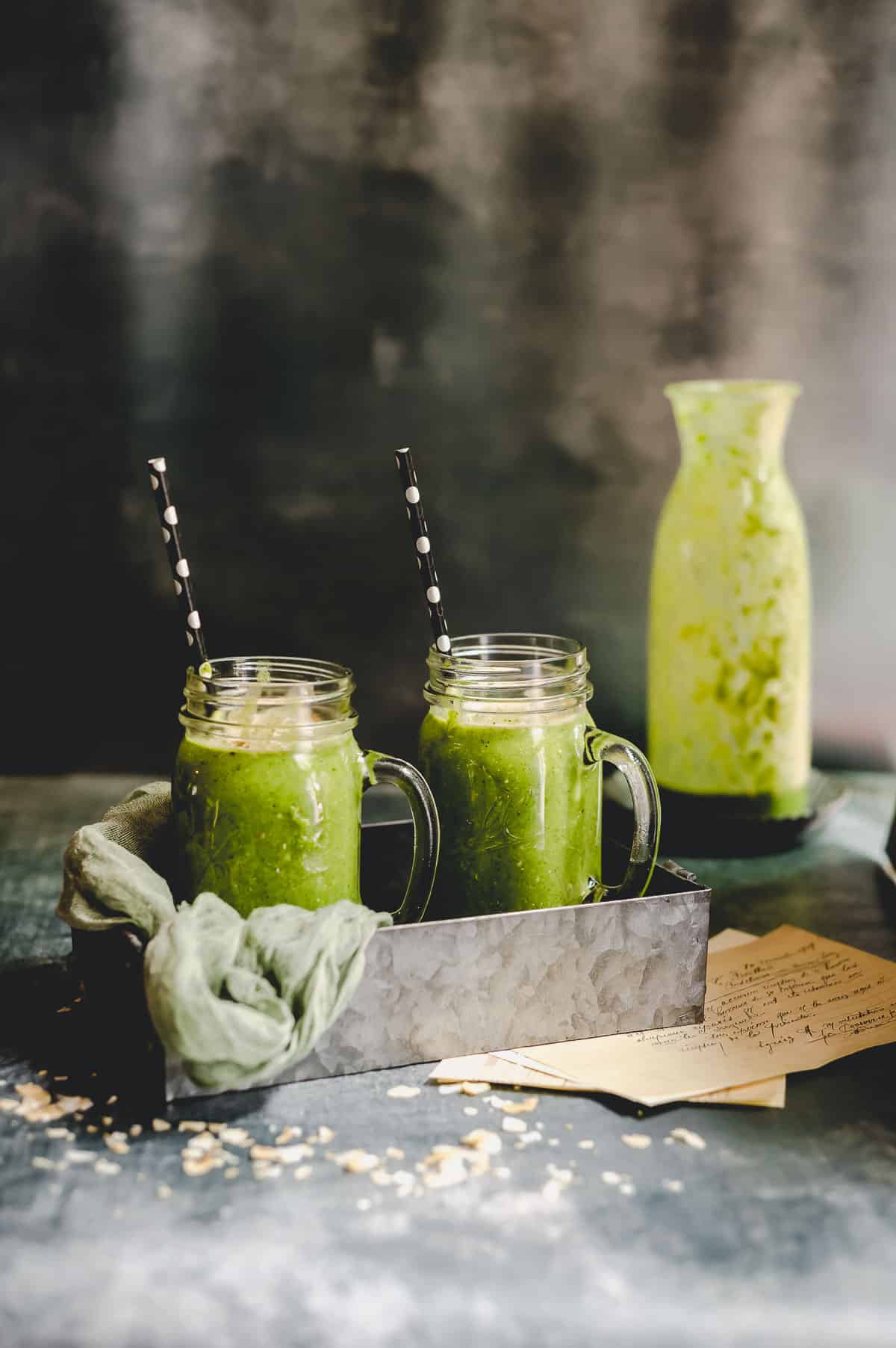 Side view of two green smoothies on a metal tray