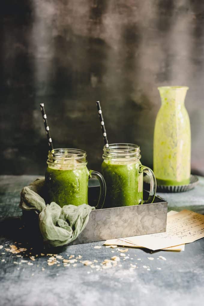 Side view of two green smoothies on a metal tray