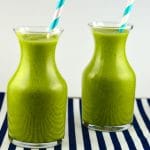 Side view of 2 small glass bottles filled with tropical green smoothie