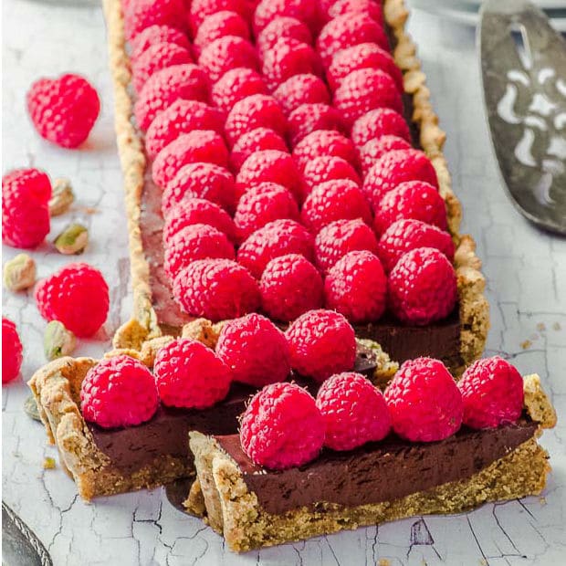 Up close view of chocolate tart covered in fresh raspberries