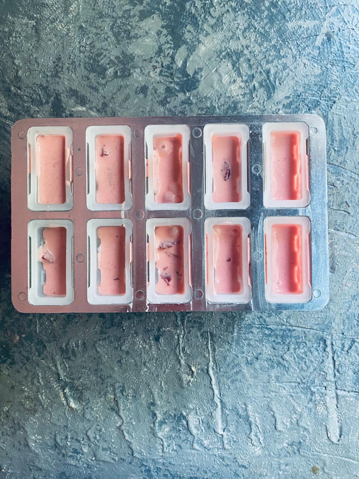 Popsicle molds filled with strawberry cheesecake ice cream