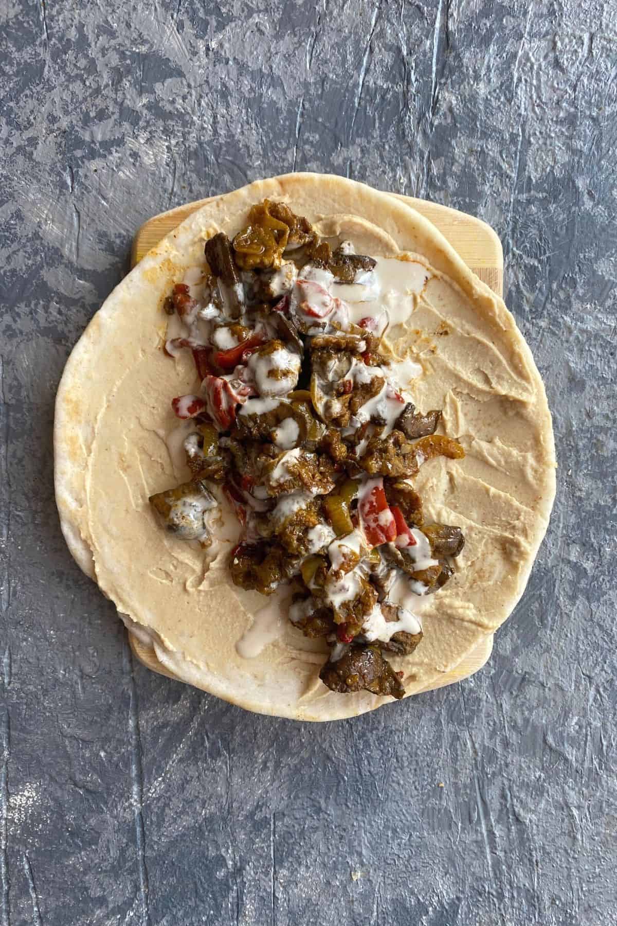 An overhead view of an open pita with all of the toppings to make a mediterranean vegan sandwich in it