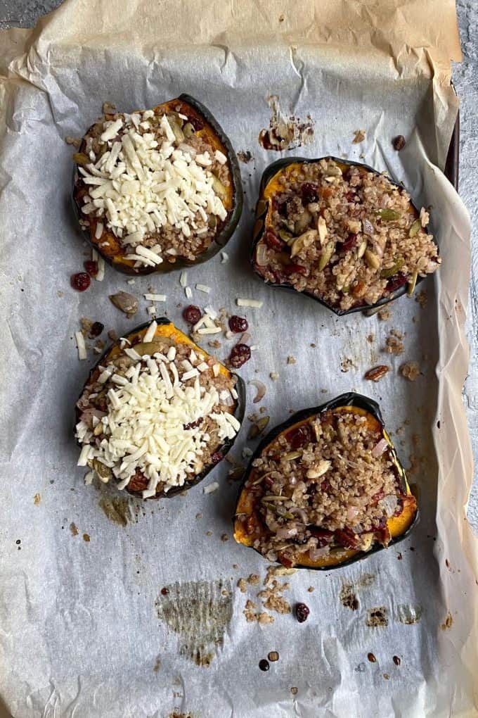 An overhead view of stuffed acorn squash on a parchment lined baking sheet