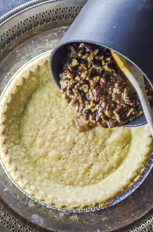 pouring pecan pie filling a a baked pie crust