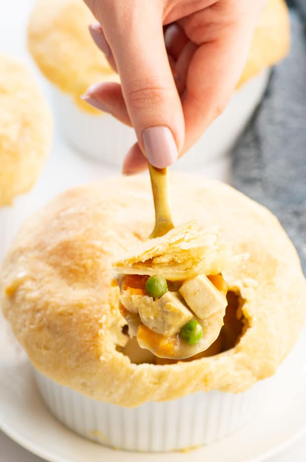 Taking a spoonful of an individually portioned vegan pot pie