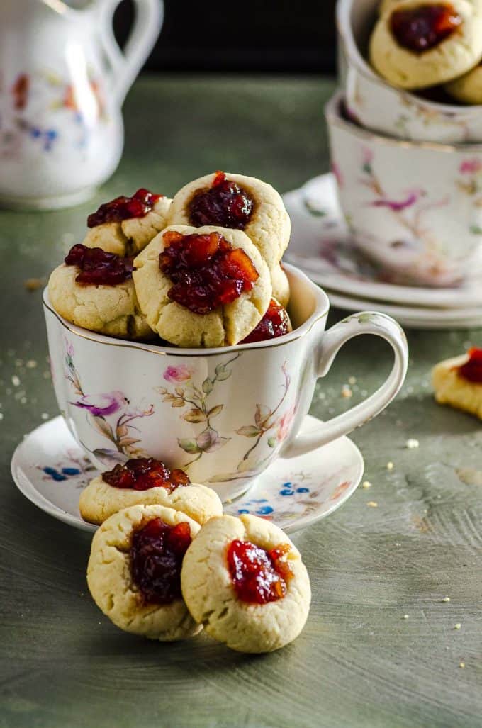 A close up of a tea cup style mug filled with thumbprint cookies