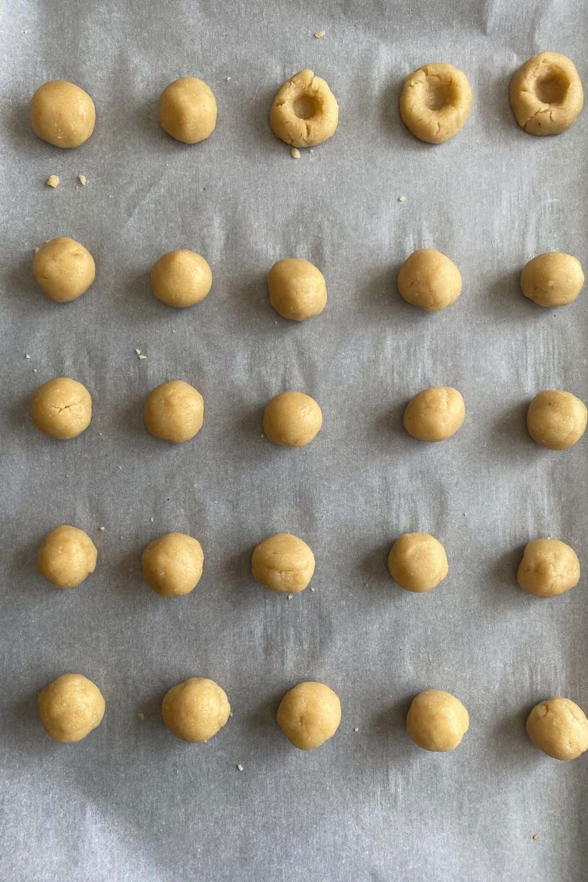 Thumbprint cookie dough balls with three with thumbprints in them